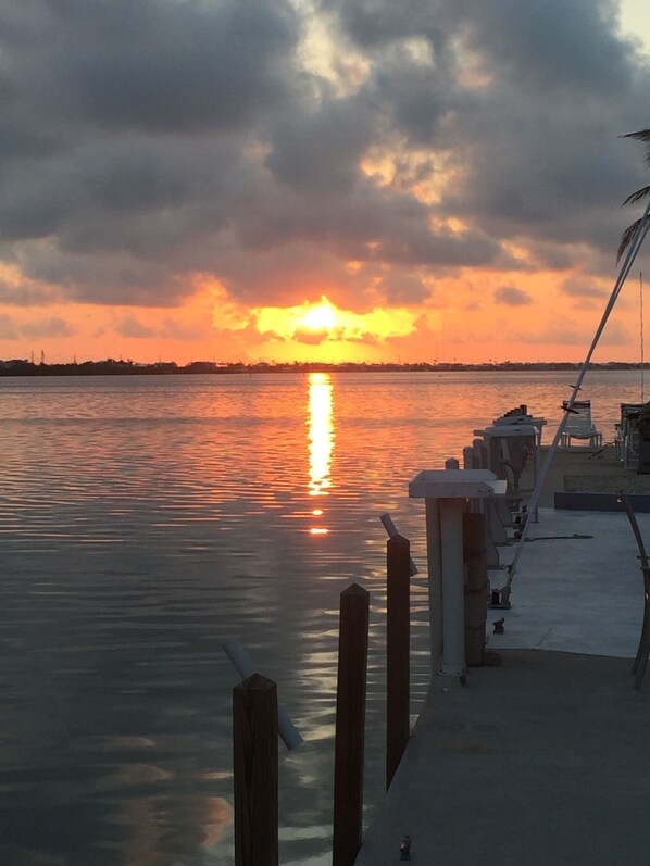 A waterfront scene with a dock extending into calm water, reflecting the sunset. - Waterfront 80' heated pool hottub Gorgeous views 20 mins to Key West & Marathon  (Cudjoe Key)