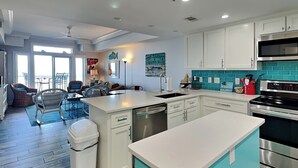 A modern kitchen with white cabinets, a teal backsplash, and stainless steel appliances.