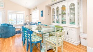 Un coin repas avec une table à plateau en verre, des chaises à rayures et un meuble blanc doté de portes en verre.