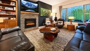 A living room with a fireplace, leather sofas, a coffee table, and a television.