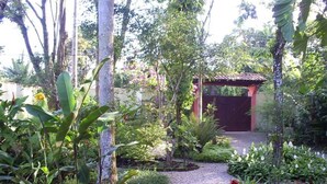 A garden with a gravel path leading to a red gate. - Nice house just 330 feet away from the beach (São Sebastião)