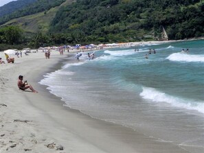 Una playa con gente, sombrillas y olas.