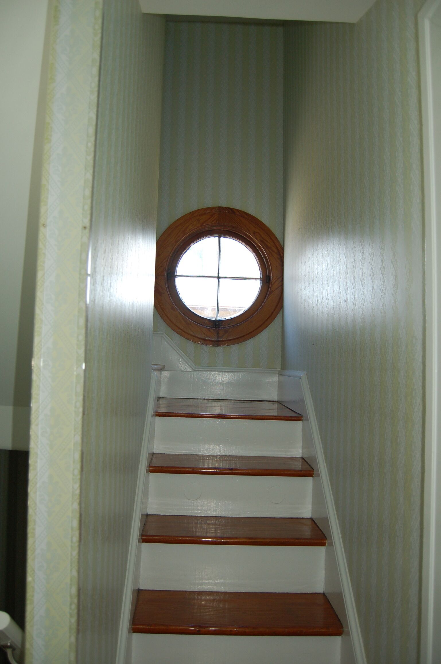 A staircase with wooden steps and a circular window at the top.