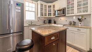 Una cocina moderna con armarios blancos, un refrigerador de acero inoxidable, un microondas y una estufa.