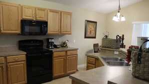 A kitchen with wooden cabinets, a black stove, a microwave, and a coffee maker.