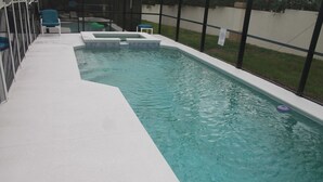 A swimming pool with a white deck and a green chair.