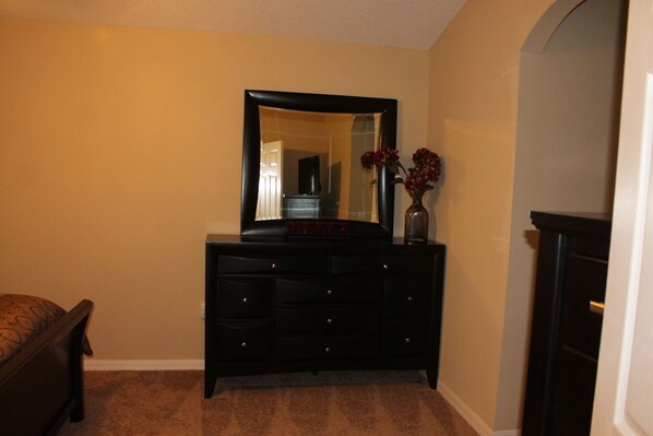 A room with a dark wooden dresser, a mirror above it, and a vase with flowers on the dresser. - **Beautiful 4bd/4bth Home W/ Pool&Hotub 9Miles Away From Attractions** (Davenport)