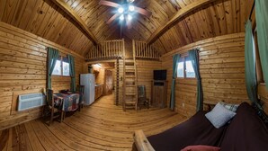A log cabin interior with a wooden floor, a sofa, a dining table, and a kitchen area. - Beautiful Romantic River front cabin with mountain views,fantastic location! (Luray)