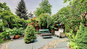Eine Gartenpatio mit Holzdeck, einer Bank und Topfpflanzen.