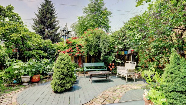 A garden patio with a wooden deck, a bench, and potted plants.