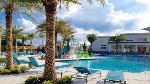 A pool area with lounge chairs, palm trees, and a building in the background.