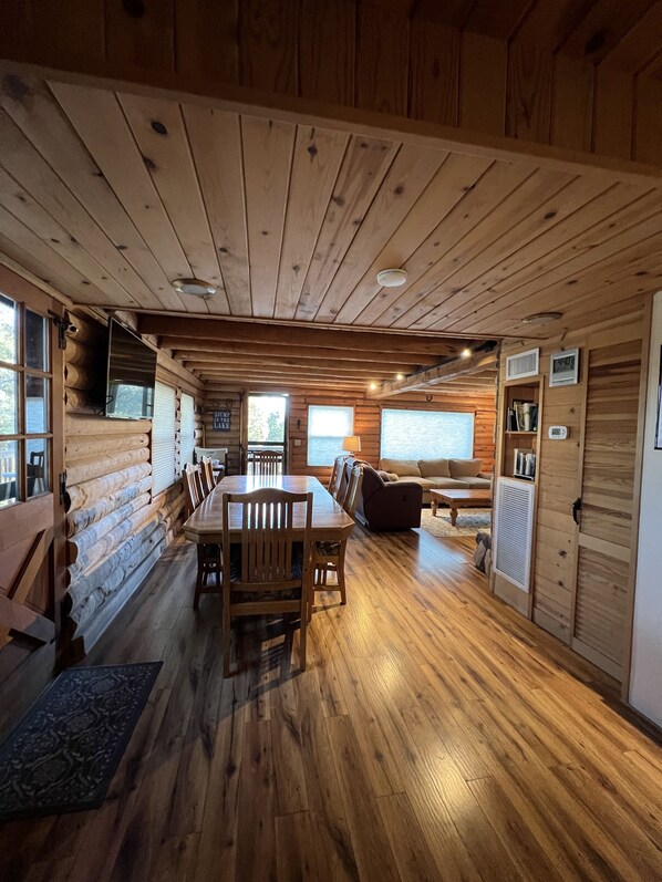 L’intérieur d’une cabane en rondins comprend un coin repas, un canapé et une cheminée.