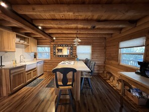 L’intérieur d’un chalet en bois comprend une cuisine, un coin repas et une grande fenêtre.