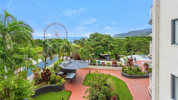 A courtyard with a pool, outdoor seating, and a Ferris wheel in the background. - Best Location in Cairns - Ocean Views (Cairns)