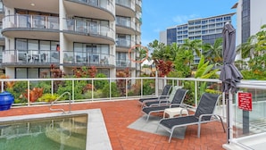 A rooftop pool area with lounge chairs, a pool, and a view of surrounding buildings. - Best Location in Cairns - Ocean Views (Cairns)