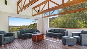 Un'ampia area relax esterna con terrazza in legno, ampie finestre con vista panoramica e un design architettonico moderno.