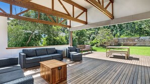 Patio esterno con decking in legno, un divano, una panca e un tavolo.