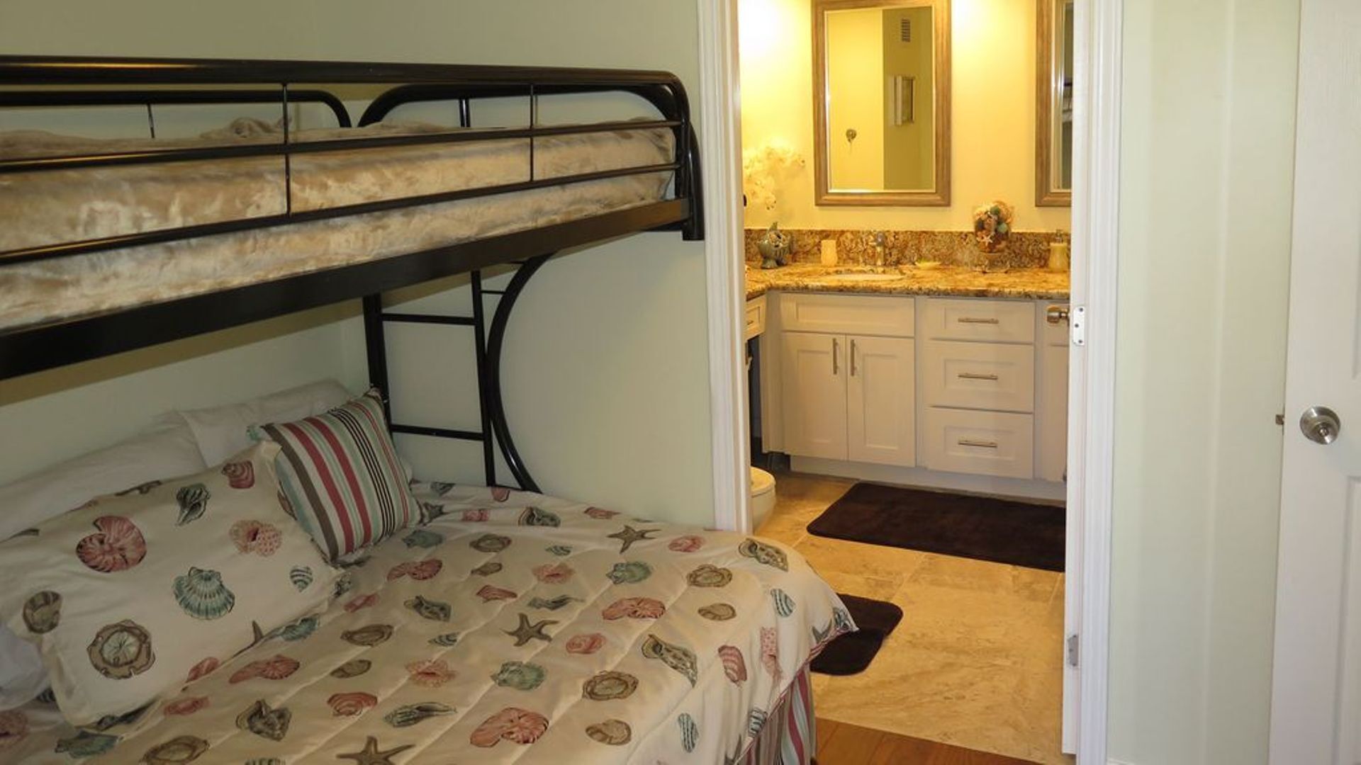 A bunk bed with a patterned bedspread, a small bedside table, and a nightstand.