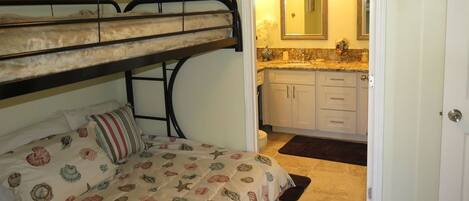 A bunk bed with a patterned bedspread, a small bedside table, and a nightstand.
