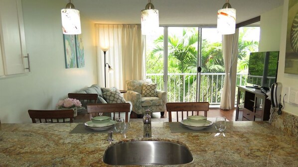 A dining area with a granite countertop, a stainless steel sink, and a seating arrangement including a sofa and chairs.