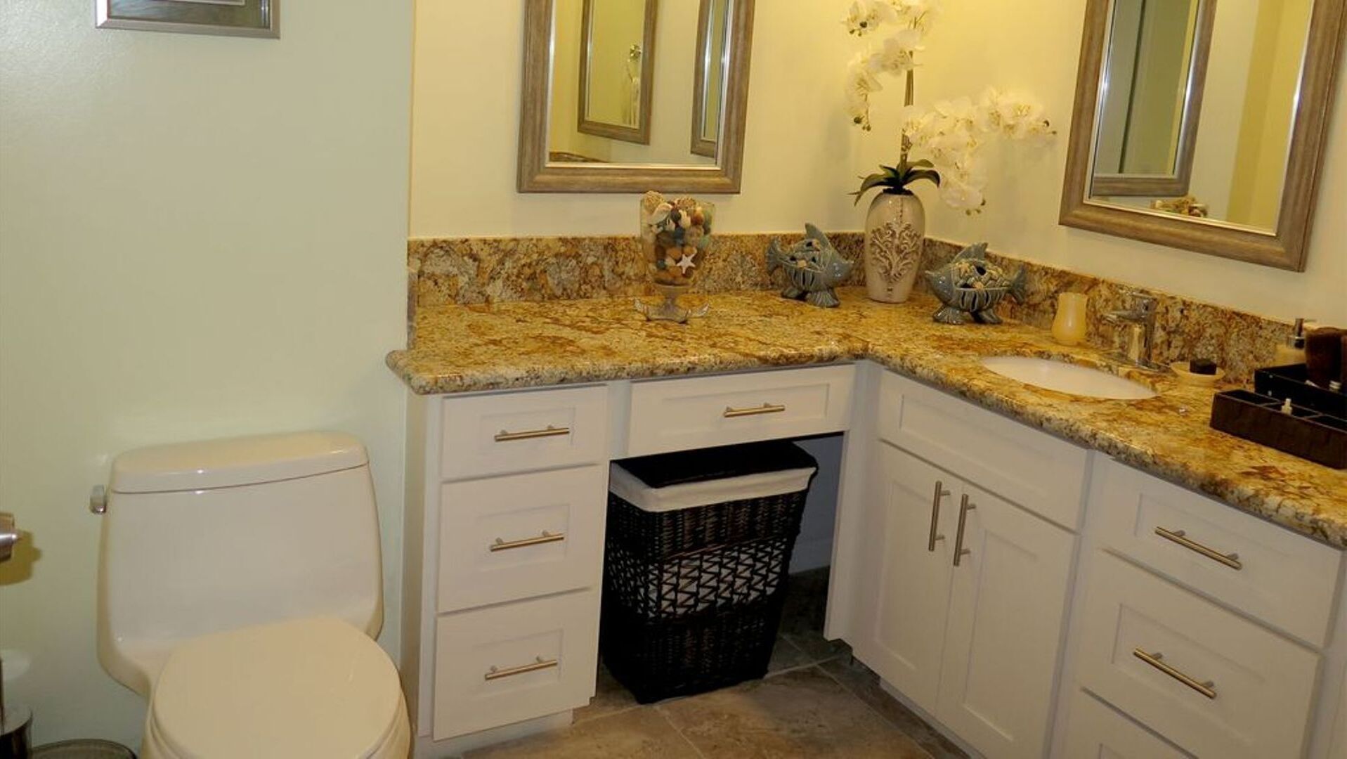 A bathroom with a toilet, a sink, and a vanity with drawers and cabinets.