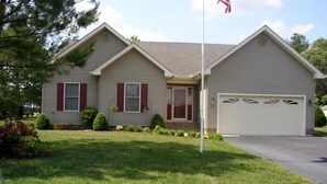 A two-story house with a front garage, a well-maintained lawn, and a flagpole.