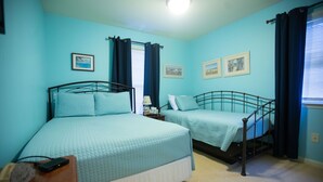 A bedroom with two beds, a nightstand, and a lamp.