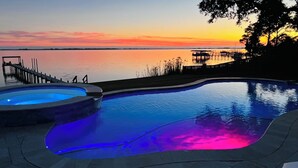 A swimming pool with a hot tub, surrounded by a deck and a view of the sunset over a body of water. - Stunning Waterfront Villa w Incredible Views - Htd Pool, Spa, Dock, Beach, Gm Rm (Mary Esther)