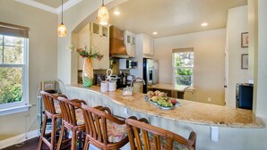 A kitchen with a large island, wooden chairs, and pendant lighting. - Stunning Waterfront Villa w Incredible Views - Htd Pool, Spa, Dock, Beach, Gm Rm (Mary Esther)