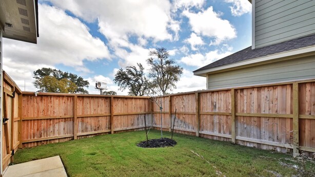 A backyard with a wooden fence, a small tree, and a concrete pathway. - Walk to Riverwalk & Alamo • Luxury Southtown 3BR • Stylish Home Near Alamodome (San Antonio)