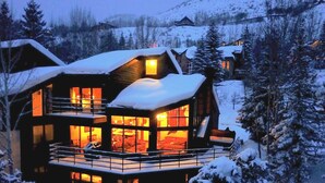 Eine mehrstöckige Holzblüke mit Balkon, umgeben von schneebedeckten Bäumen.