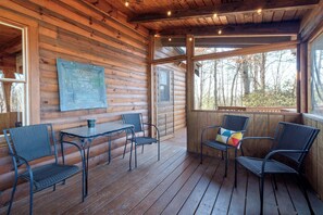 Eine Holzhütte mit einer Holzterrasse, einem Tisch mit Stühlen und einer Tafel mit Schrift.