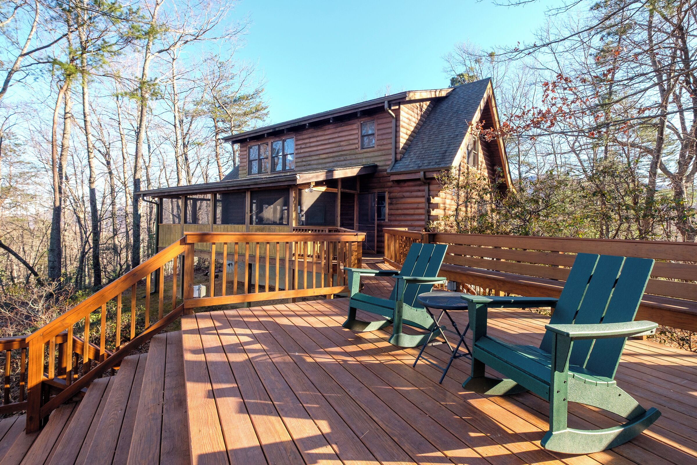 A wooden deck with two Adirondack chairs and a wooden railing.