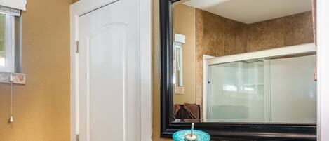 A bathroom with a large mirror, a blue glass bowl sink, dark cabinets, and a beige wall.