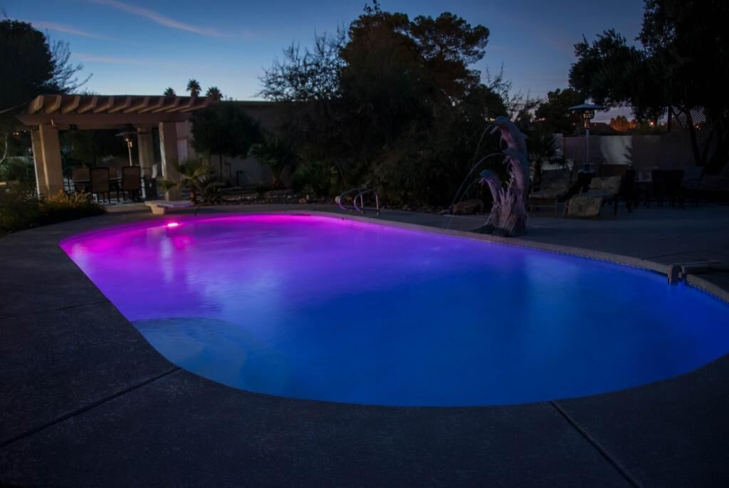Una piscina de borde curvo y una estructura de pérgola al fondo.
