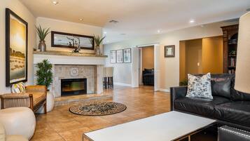 A spacious living room with a fireplace, leather sofa, and a coffee table.