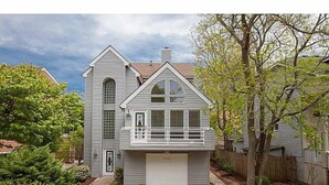 A two-story house with a garage, a front porch, and a large window. - Big Kitchen, Two Masters, Hot Tub, Short Walk from Croatan Beach (Virginia Beach)