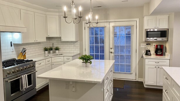 A modern kitchen with white cabinetry, a central island, a stove, and a microwave. - Big Kitchen, Two Masters, Hot Tub, Short Walk from Croatan Beach (Virginia Beach)