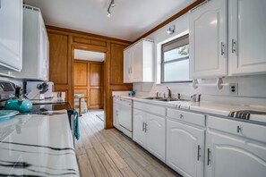 Enjoy cooking in this well-equipped kitchen with a stainless steel sink, white cabinetry, and a convenient countertop.