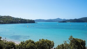 A coastal landscape with clear turquoise waters, a beach, and hills in the distance. - Frangipani Lodge 207, Beachfront Apartment on Hamilton Island (Hamilton Island)