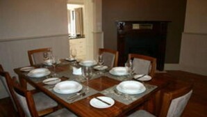 A dining table set with plates, glasses, and cutlery, surrounded by chairs. - Bluebells Cottage Central Albury (Albury)