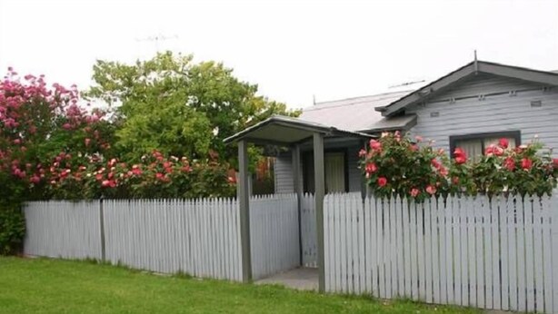 A house with a white picket fence, a covered porch, and blooming pink flowers. - Bluebells Cottage Central Albury (Albury)