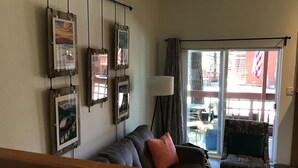 A living room with a sofa, a chair, and a glass door leading to an outdoor area.
