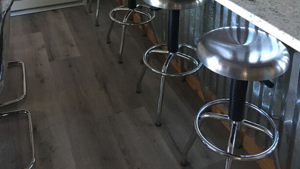 A kitchen with a bar stool area, a stove, and a spice rack on the wall.