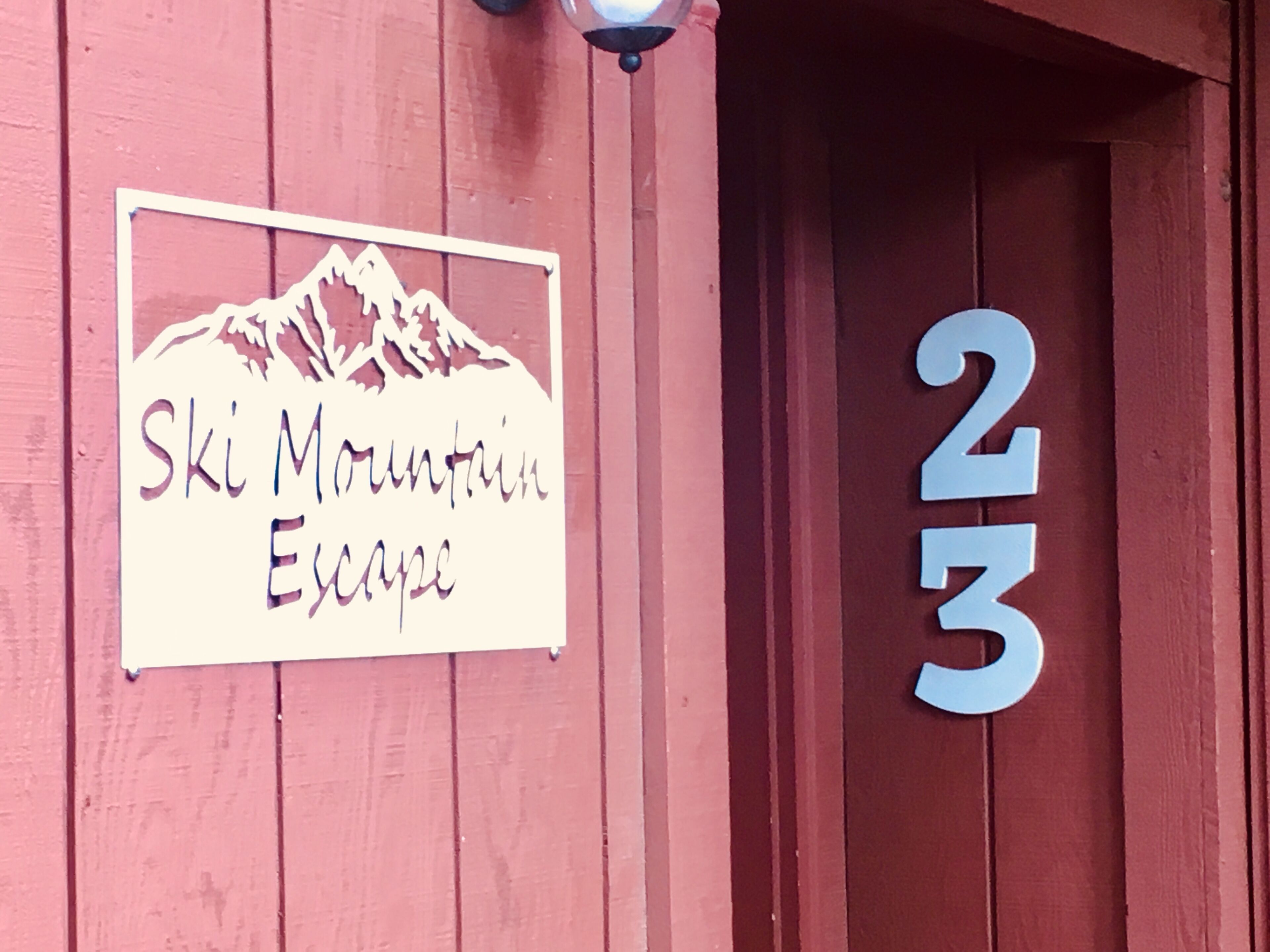 Un letrero con la frase 'Ski Mountain Escape' y el número '312' en una pared de madera.