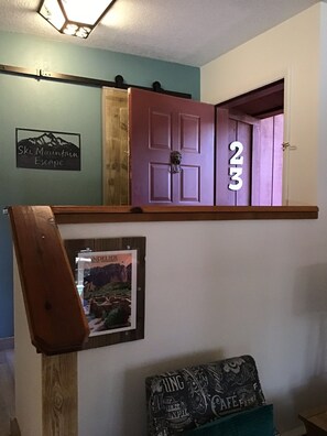 Une pièce dotée d’une porte en bois portant le numéro 23, d’une enseigne indiquant « Ski Mountain Escape » et d’une affiche représentant le « Monument national ».