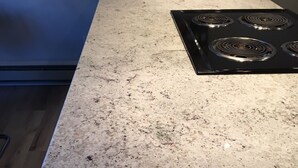 A kitchen with a granite countertop, a black stove, and a spice rack on the wall.