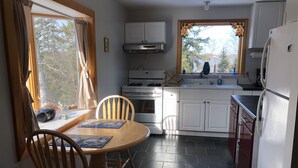 Una cocina con una mesa de comedor, sillas, estufa y refrigerador.