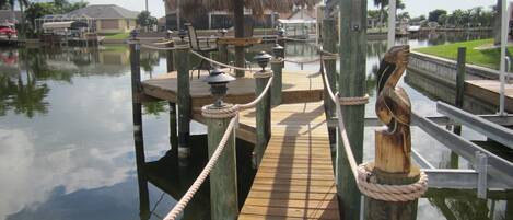 A wooden dock with a rope barrier, a thatched-roof structure, and a wooden statue.