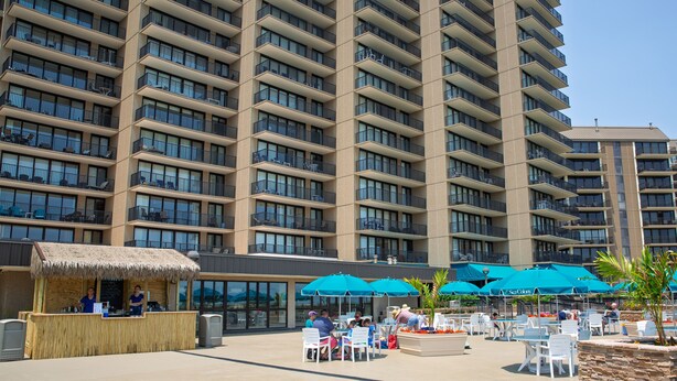 A hotel with multiple balconies, outdoor seating areas with umbrellas, and a small food kiosk. - Sea Colony Oceanfront 1 Bedroom Condo Beautiful View Sept 21 -25 Super Special  (Bethany Beach)